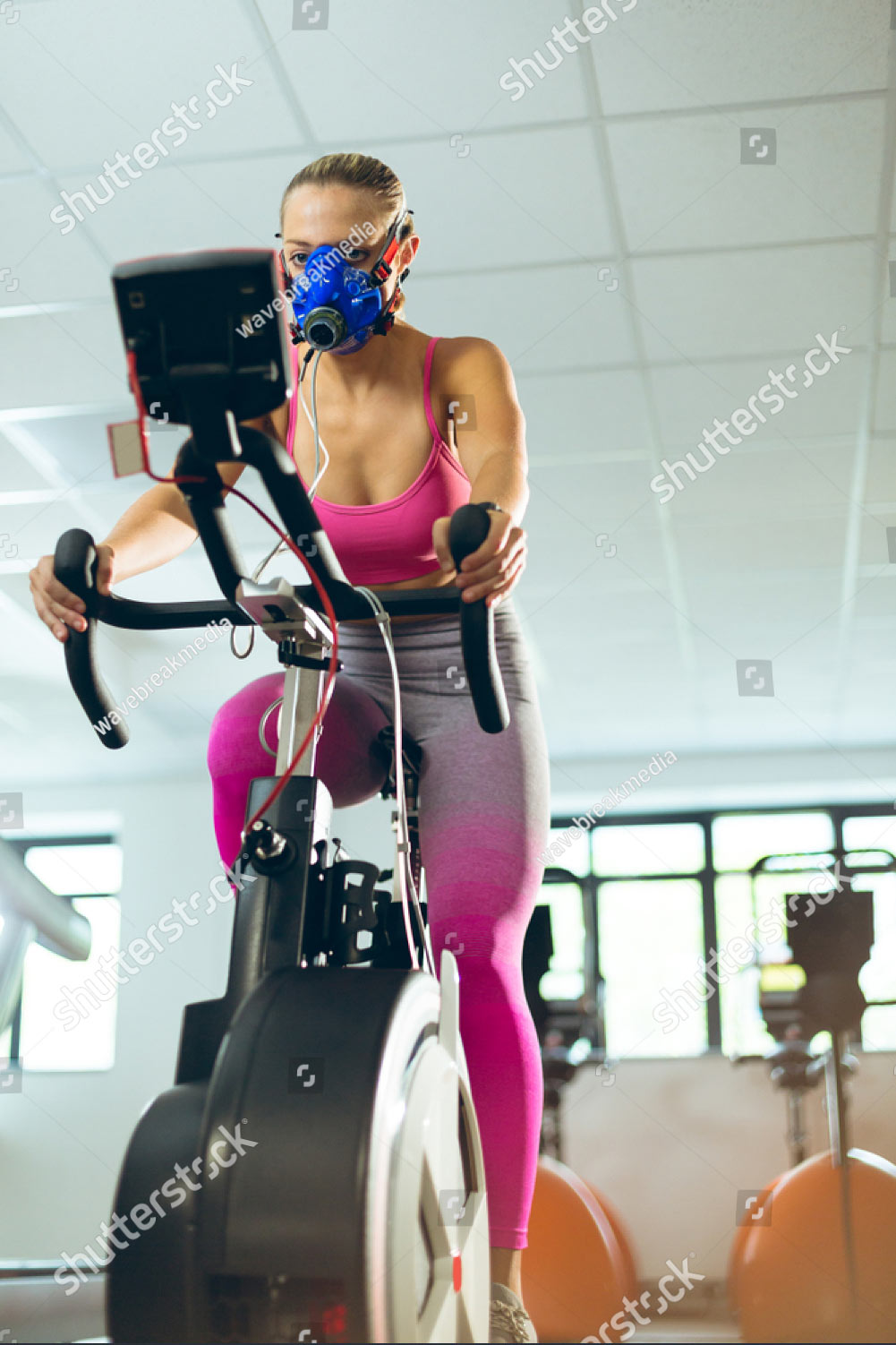 low-angle-view-of-beautiful-young-caucasian-female-athlete-with-oxygen-mask-exercising-with-1460401328